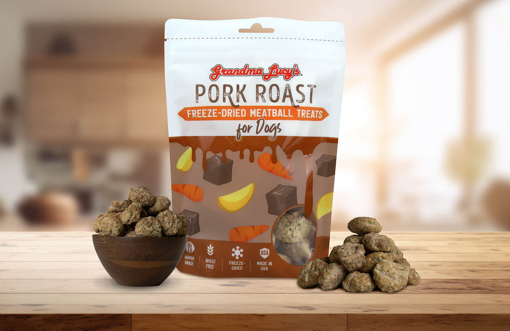 Grandma Lucy's Pork Roast Meatball dog treat bag displayed on a kitchen counter alongside a bowl filled with meatballs.